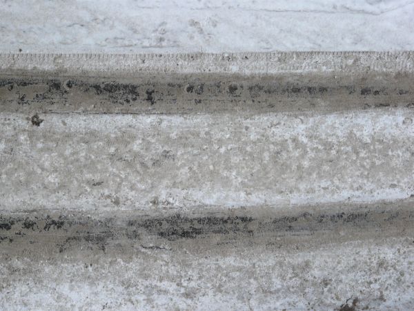 Texture of road in white snow with tire marks and dirty surface.